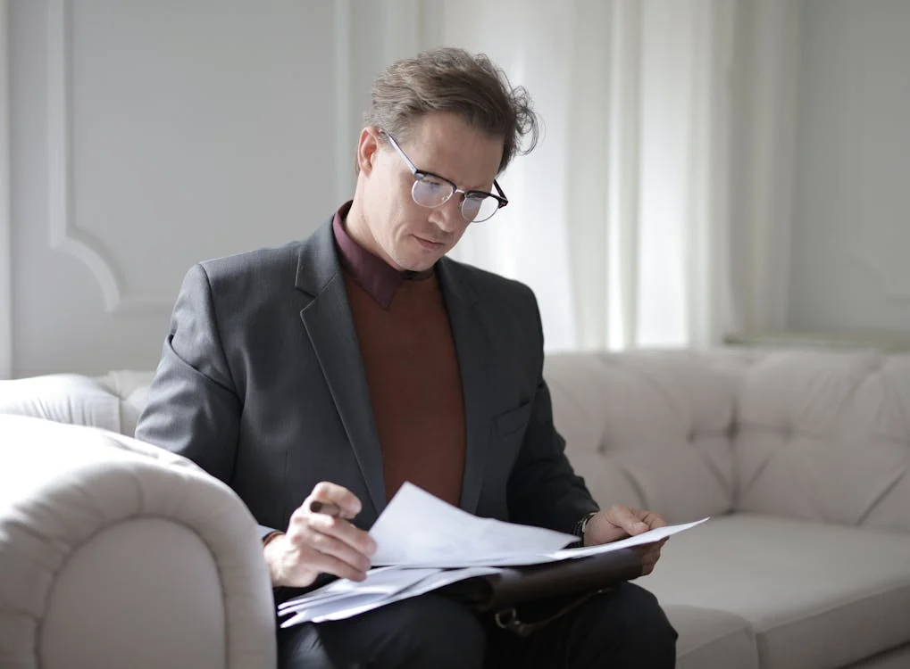 a man in a blazer holding a document.