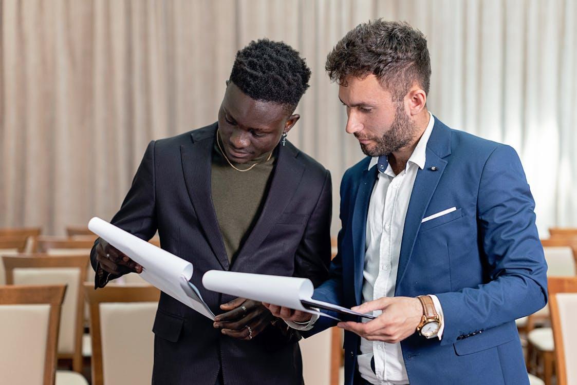 Two businessmen in suits reviewing documents during a professional meeting.